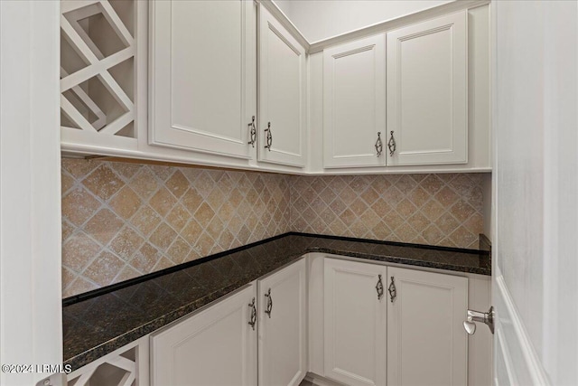 kitchen featuring white cabinetry, dark stone countertops, and backsplash