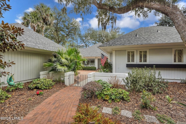 view of front of property with a shingled roof, a gate, and fence