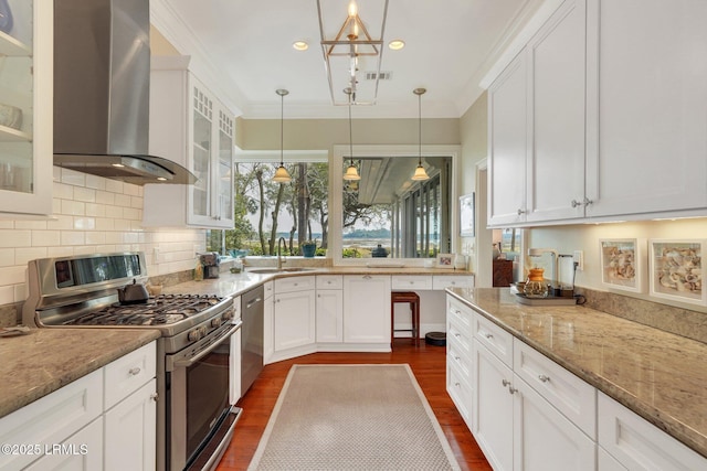 kitchen with wall chimney range hood, appliances with stainless steel finishes, glass insert cabinets, and white cabinets