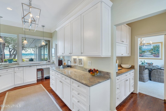 kitchen with decorative light fixtures, dark wood-type flooring, white cabinets, a sink, and light stone countertops