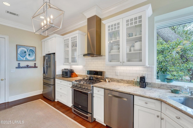 kitchen featuring white cabinetry, wall chimney exhaust hood, glass insert cabinets, and stainless steel appliances