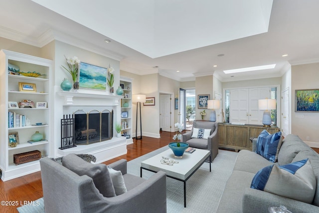 living area featuring crown molding, built in features, a fireplace with raised hearth, and dark wood-style flooring