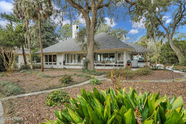 rear view of property with a shingled roof and a chimney