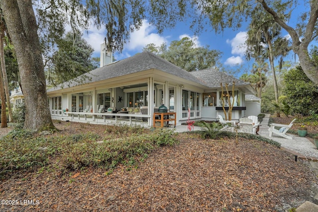 view of front facade with a patio, french doors, and roof with shingles