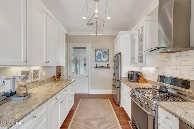 kitchen with light stone counters, stainless steel appliances, glass insert cabinets, white cabinetry, and wall chimney exhaust hood