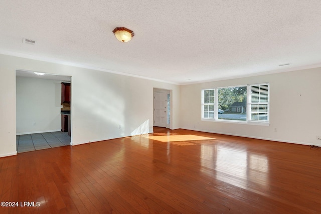 spare room with crown molding, light hardwood / wood-style flooring, and a textured ceiling