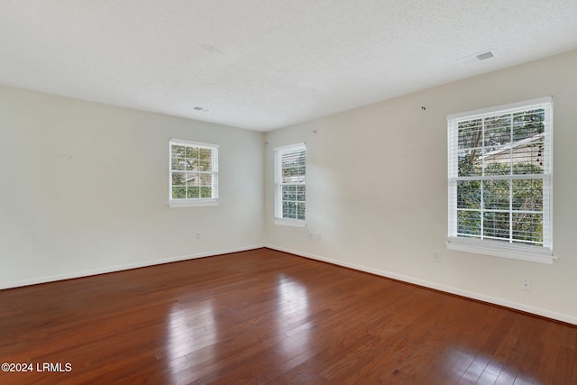 unfurnished room with hardwood / wood-style flooring, a textured ceiling, and a wealth of natural light