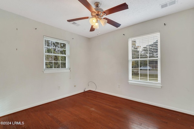 empty room featuring wood-type flooring, a wealth of natural light, a textured ceiling, and ceiling fan