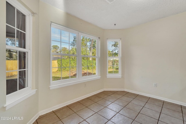 tiled empty room featuring a textured ceiling