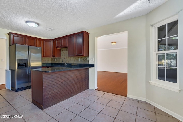 kitchen with light tile patterned floors, decorative backsplash, a textured ceiling, and stainless steel fridge with ice dispenser