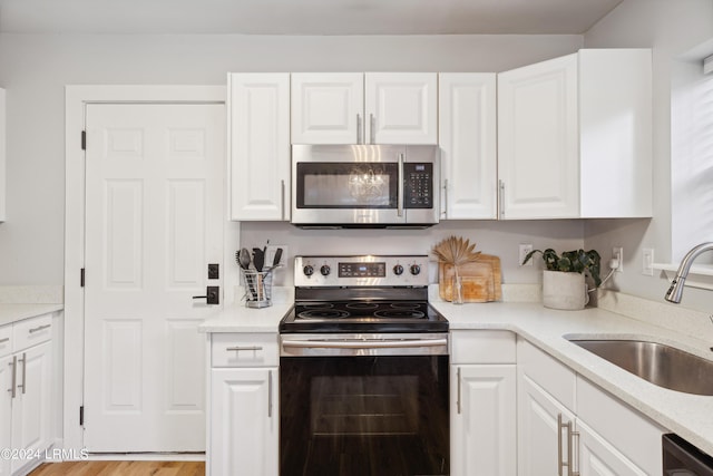 kitchen with light stone counters, sink, white cabinets, and appliances with stainless steel finishes