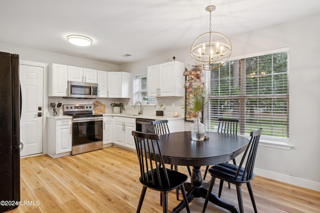 kitchen featuring white cabinetry, decorative light fixtures, a chandelier, light wood-type flooring, and stainless steel appliances