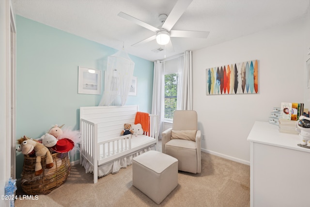 carpeted bedroom with a nursery area and ceiling fan