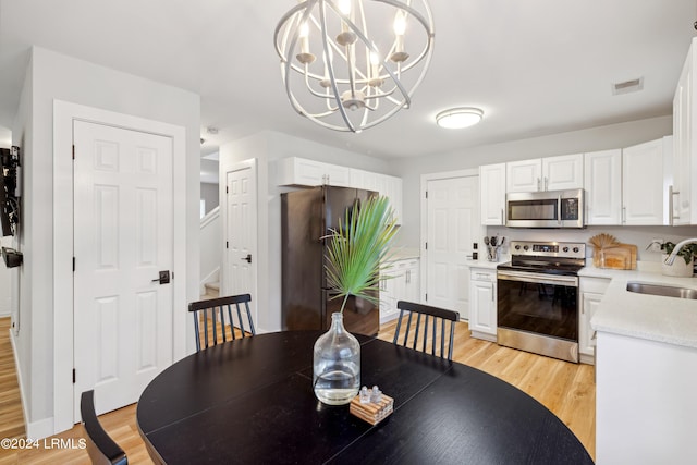 dining space with a notable chandelier, sink, and light wood-type flooring