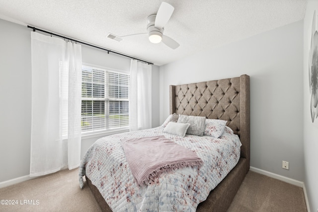 bedroom with ceiling fan, carpet flooring, and a textured ceiling