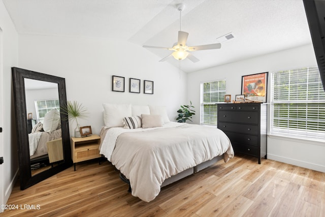 bedroom with lofted ceiling, multiple windows, light hardwood / wood-style floors, and ceiling fan