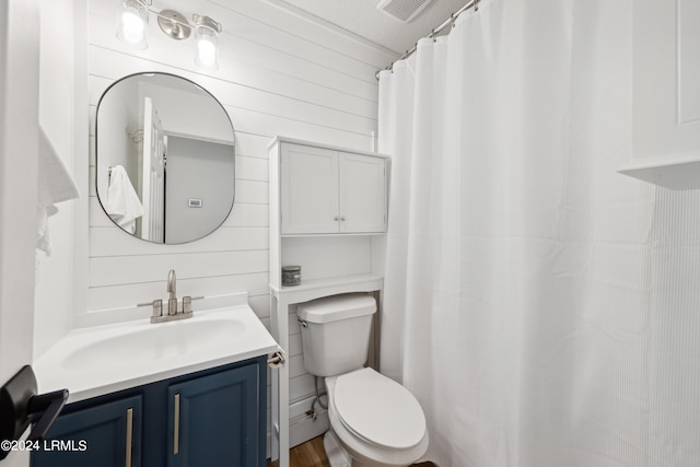 bathroom featuring vanity, a textured ceiling, wooden walls, and toilet