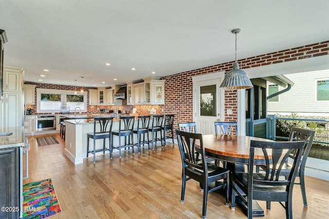 dining space featuring light wood-type flooring, brick wall, and recessed lighting