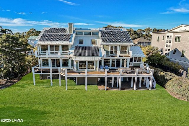 rear view of property featuring metal roof, solar panels, a yard, and a balcony