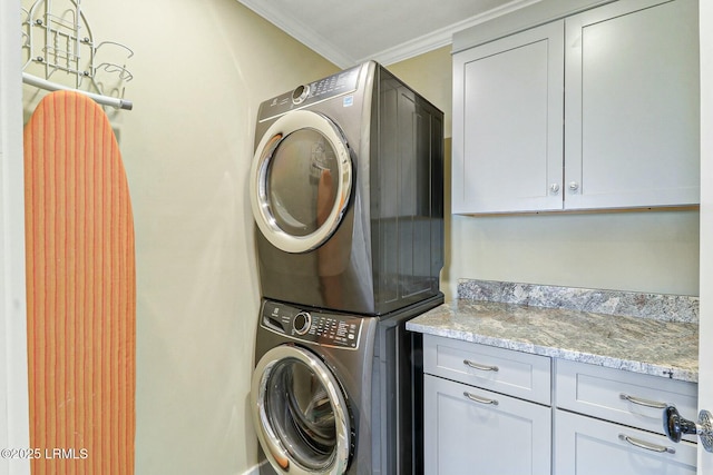 laundry room with stacked washer / drying machine, cabinet space, and crown molding