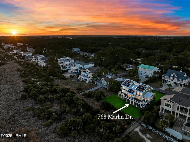 aerial view at dusk featuring a wooded view