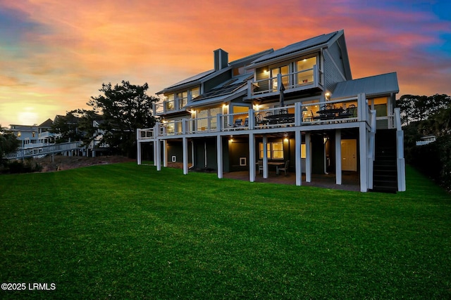 rear view of house featuring a patio area, a yard, a chimney, and a wooden deck