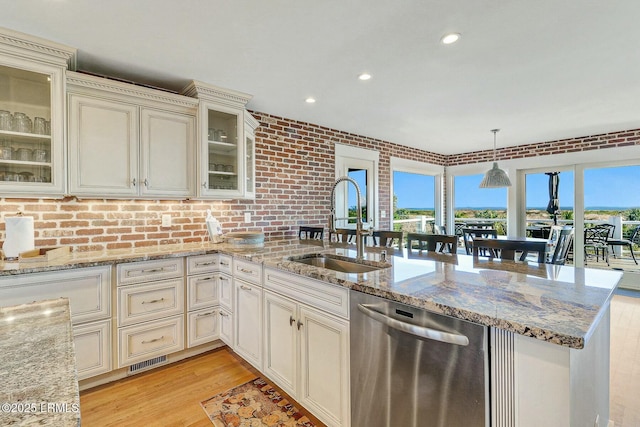 kitchen featuring visible vents, a sink, light wood-type flooring, dishwasher, and a peninsula