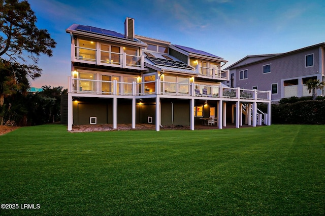 back of house with a deck, a yard, stairway, and roof mounted solar panels