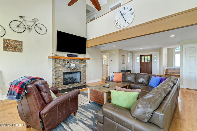 living area featuring baseboards, a towering ceiling, wood finished floors, a fireplace, and recessed lighting