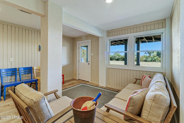 interior space with plenty of natural light, wood finished floors, visible vents, and wooden walls