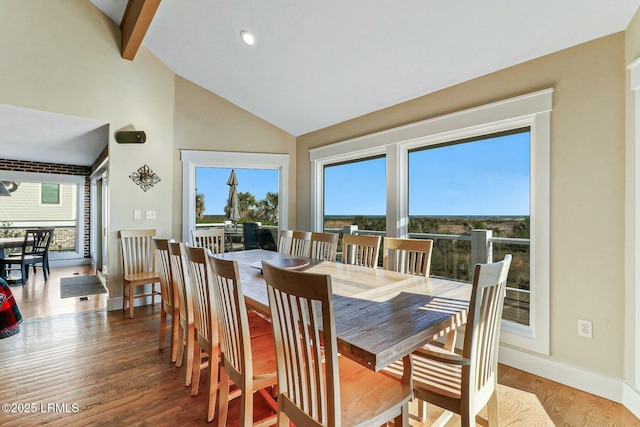 dining room featuring a healthy amount of sunlight, high vaulted ceiling, baseboards, and wood finished floors