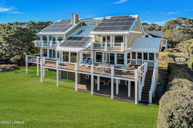 rear view of house with a lawn, stairway, metal roof, and solar panels