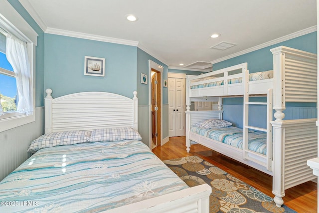 bedroom with recessed lighting, wood finished floors, visible vents, ornamental molding, and wainscoting