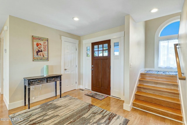 foyer entrance with light wood finished floors, stairway, baseboards, and recessed lighting