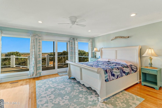 bedroom with ornamental molding, wood finished floors, visible vents, and access to exterior