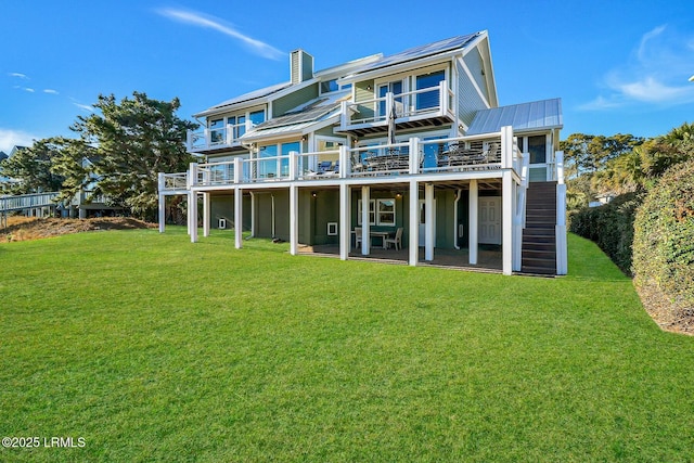 back of property with a lawn, a chimney, metal roof, a standing seam roof, and a deck