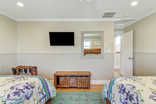 bedroom with visible vents, wainscoting, wood finished floors, crown molding, and recessed lighting