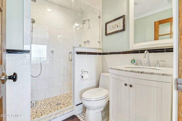 bathroom with toilet, ornamental molding, vanity, a shower stall, and tile walls