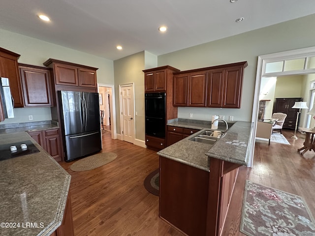 kitchen featuring a breakfast bar, sink, dark hardwood / wood-style floors, kitchen peninsula, and black appliances