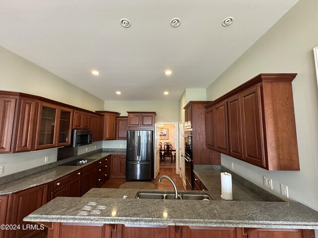 kitchen featuring sink, a breakfast bar area, black appliances, and kitchen peninsula