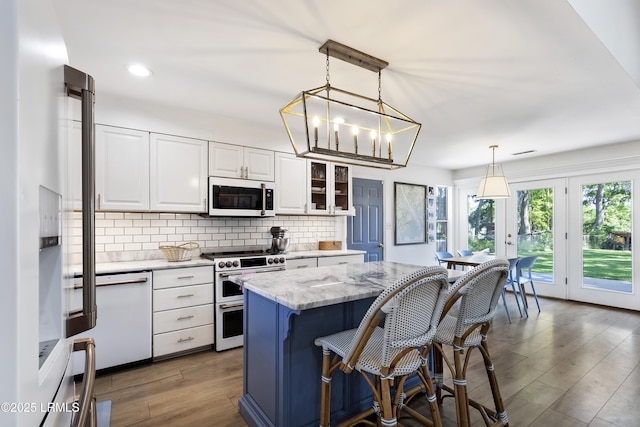 kitchen with high end appliances, light stone counters, decorative light fixtures, and white cabinets