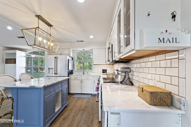 kitchen with light stone counters, decorative light fixtures, stainless steel appliances, and white cabinets