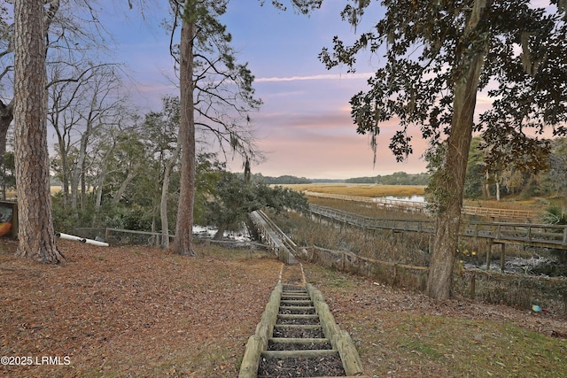 yard at dusk featuring a rural view and a water view