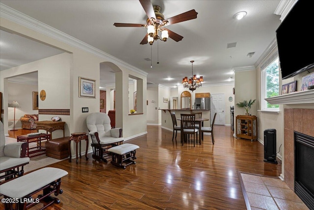 10 Screven Ct, Bluffton, SC 29909 - living room featuring a ceiling fan, crown molding, a tiled fireplace, arched walkways, and wood finished floors