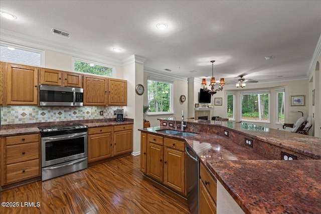 10 Screven Ct, Bluffton, SC 29909 - kitchen featuring stainless steel appliances, a sink, crown molding, a fireplace, and brown cabinetry