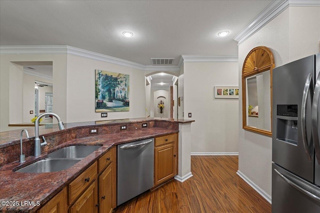 10 Screven Ct, Bluffton, SC 29909 - kitchen featuring appliances with stainless steel finishes, a sink, brown cabinetry, dark wood finished floors, and dark stone counters