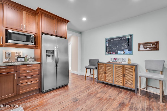 kitchen featuring appliances with stainless steel finishes, light wood-type flooring, and light stone counters