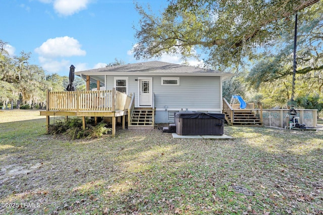 back of house featuring a hot tub, a wooden deck, and a yard