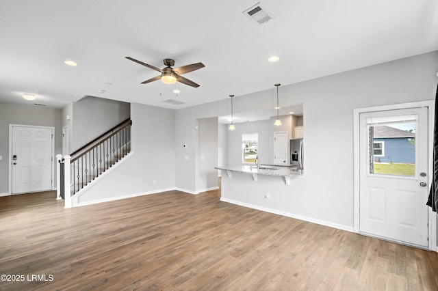 23 Toxaway Ln, Beaufort, SC 29906 - unfurnished living room with stairway, wood finished floors, ceiling fan, baseboards, and visible vents