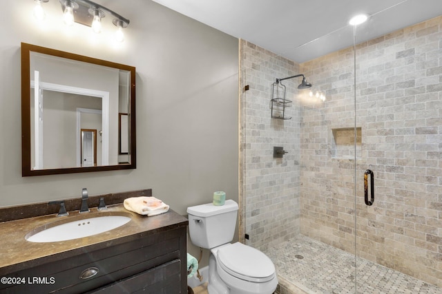 bathroom with vanity, a shower with shower door, and toilet